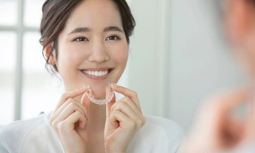 マウスピースを手に持って確認する女性のイメージ写真